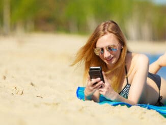 Junge Frau mit Handy an der Ostsee