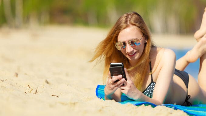 Junge Frau mit Handy an der Ostsee