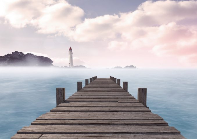Bootssteg mit Leuchtturm im Hintergrund an der Ostsee